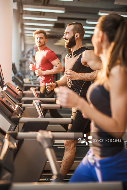 在健身俱乐部跑步机上锻炼的年轻人图片素材