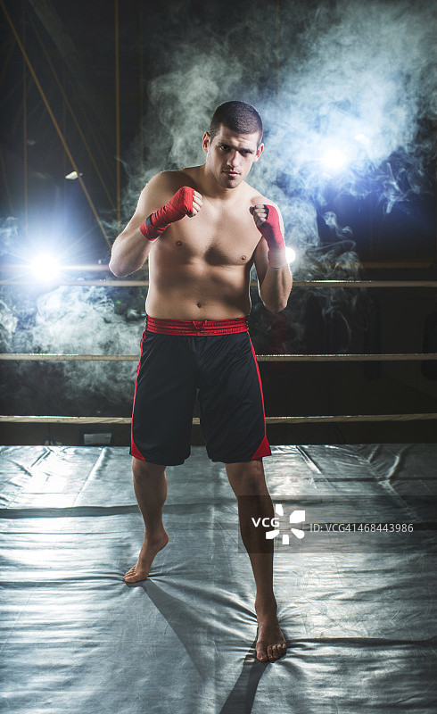 拳击手以战斗姿势站在拳击台上。图片素材