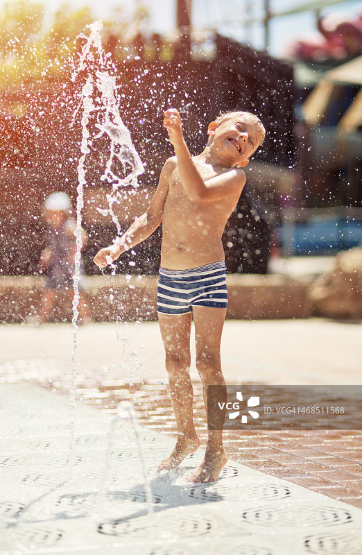 小男孩在水上乐园的喷泉里玩耍图片素材