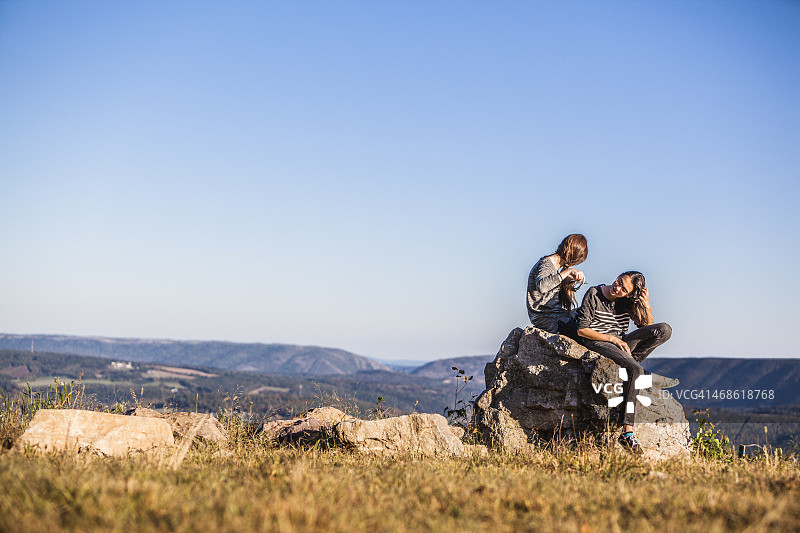 两个十几岁的女孩坐在最高的岩石上图片素材