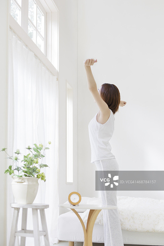 年轻女人在卧室里伸展身体图片素材