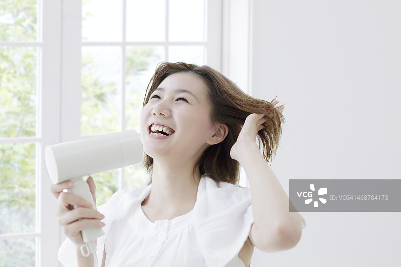 年轻女人吹干头发图片素材