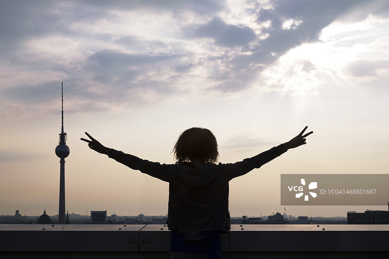 德国柏林，年轻女子在屋顶露台上举起手臂图片素材