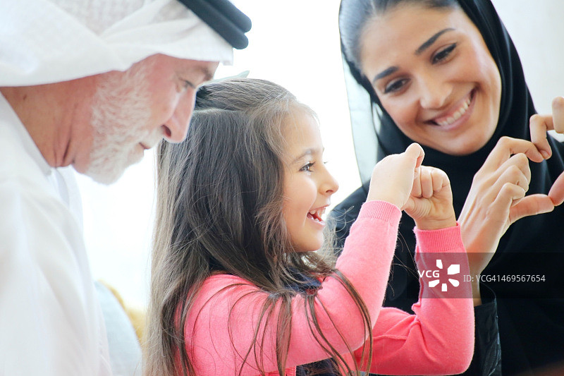 在咖啡馆用手比心的阿拉伯家庭图片素材