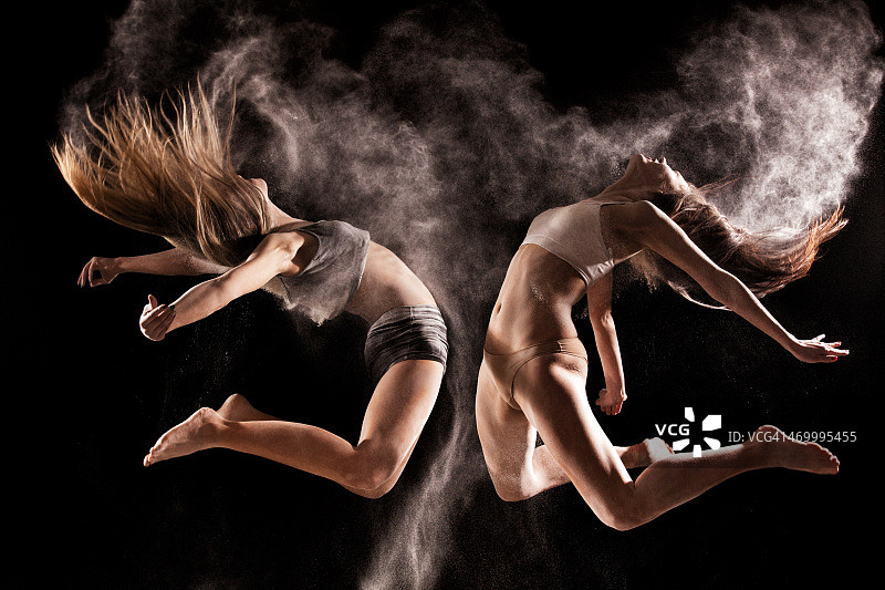 两名女子在粉末云中跳跃图片素材
