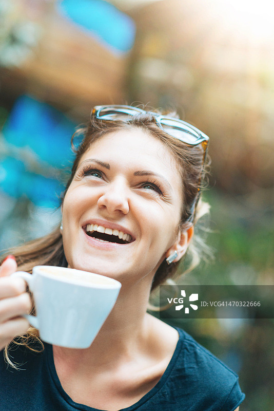 在户外咖啡馆喝咖啡微笑的白人女子图片素材