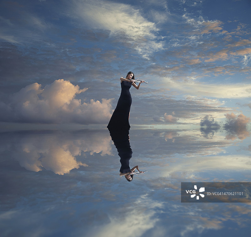 拉小提琴的白人女性在静止的湖面上的倒影图片素材