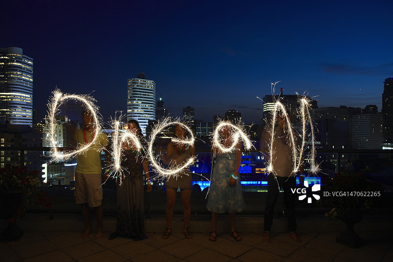 朋友们在城市屋顶上用烟花写“梦想”图片素材