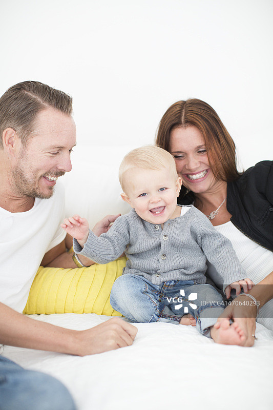 幸福的父母在床上和儿子玩耍图片素材