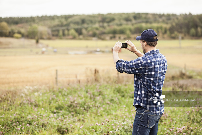 农民用手机拍摄田野的后视图图片素材