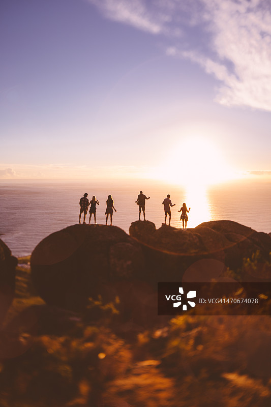 海边岩石上的青少年剪影与日落图片素材