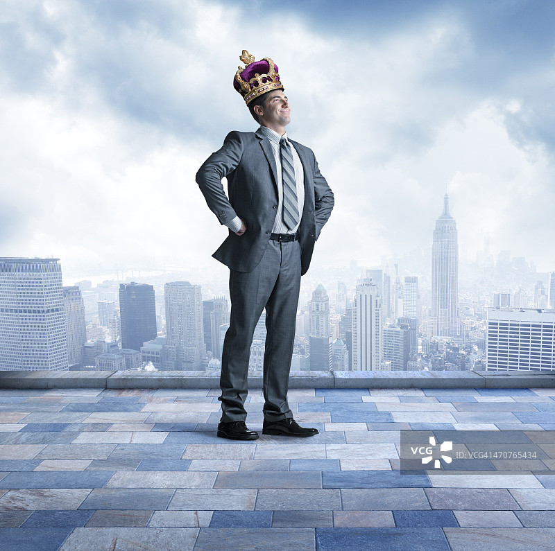 商务人士自豪地戴着王冠，以大城市天际线为背景图片素材