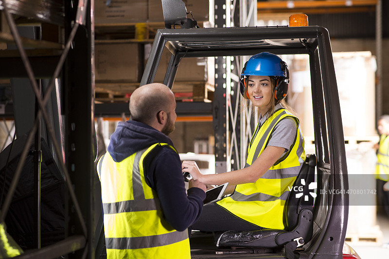 在仓库里和主管聊天的女叉车司机图片素材