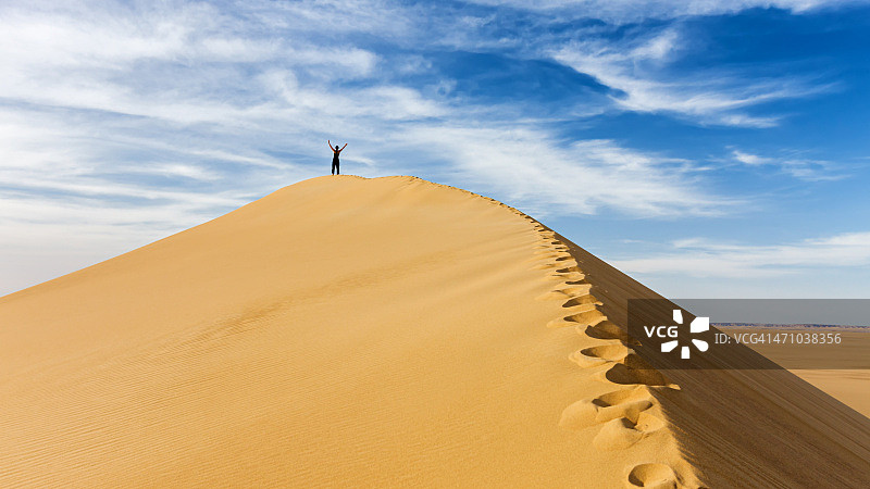 在撒哈拉沙漠沙丘顶部的女游客图片素材