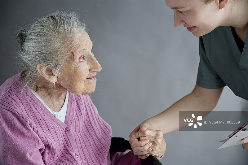 老妇人握着她的护士的手图片素材