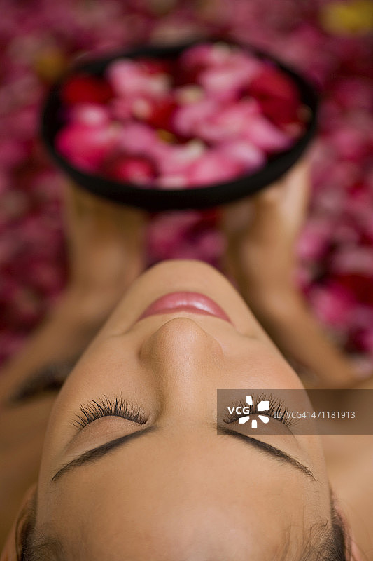 在水疗浴缸里手捧鲜花的性感女人图片素材