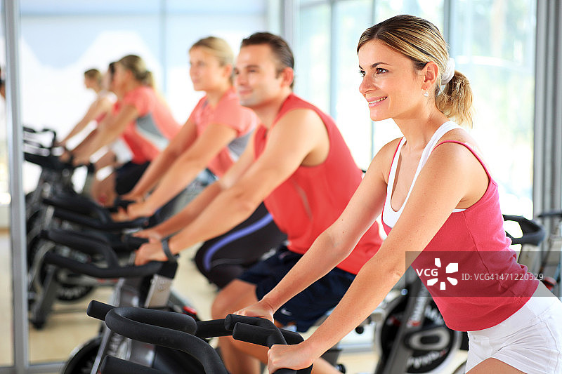 在现代健身房里骑自行车锻炼的人们图片素材