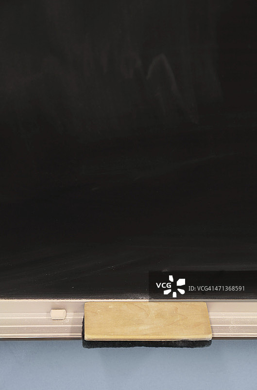 蓝色墙壁上的黑板、刷子和粉笔图片素材