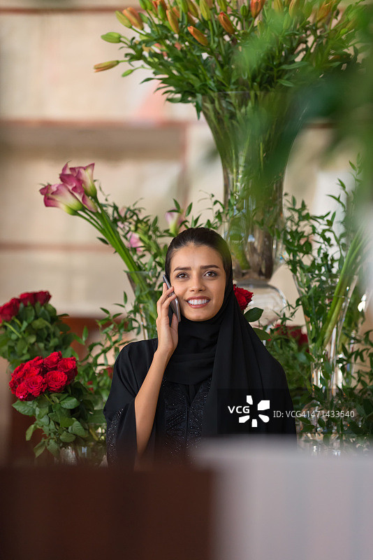 身着传统服饰的中东妇女用手机通话图片素材