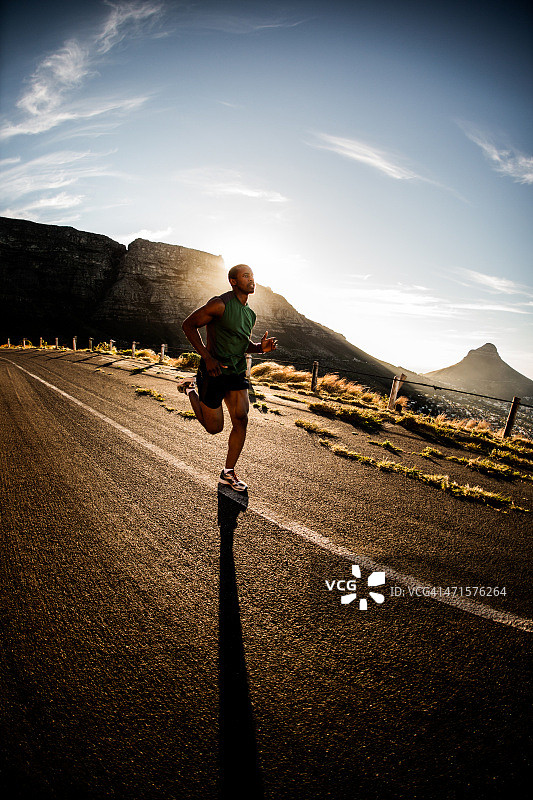 在空旷道路上跑步的健壮运动员图片素材