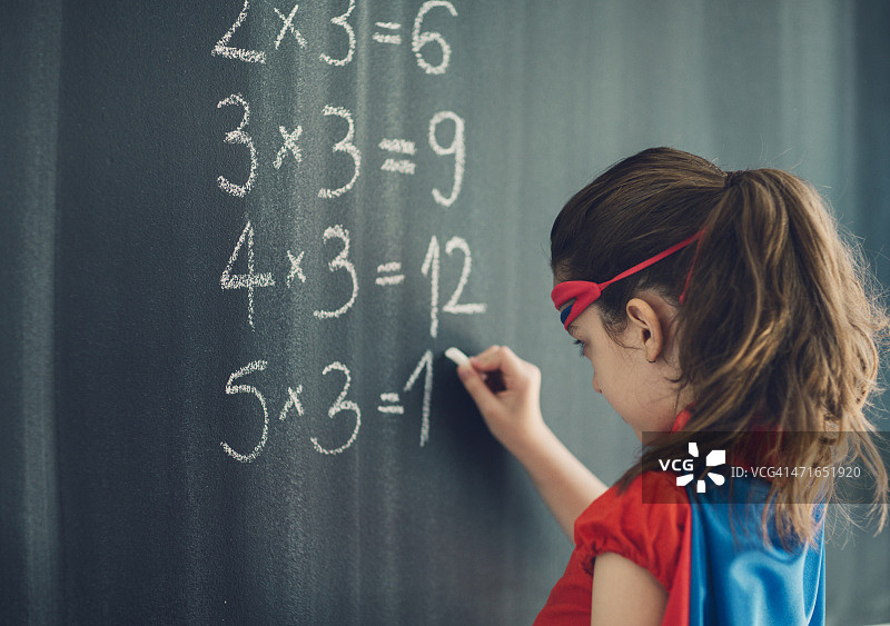 在黑板上写乘法表的超级英雄小女孩图片素材