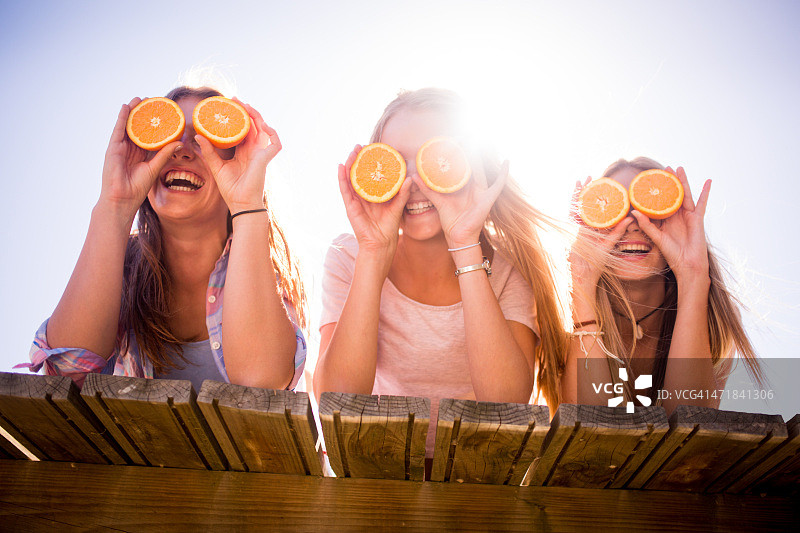 少女朋友们拿着橙子挡住眼睛图片素材