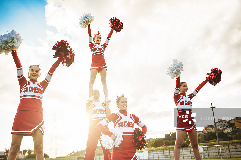 快乐的啦啦队员手持绒球摆姿势图片素材