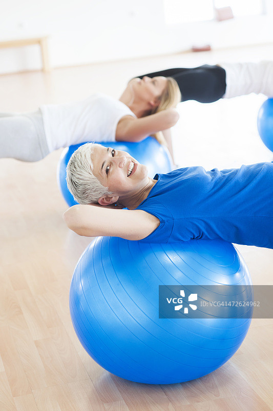 女人在健身房的蓝色球上锻炼图片素材