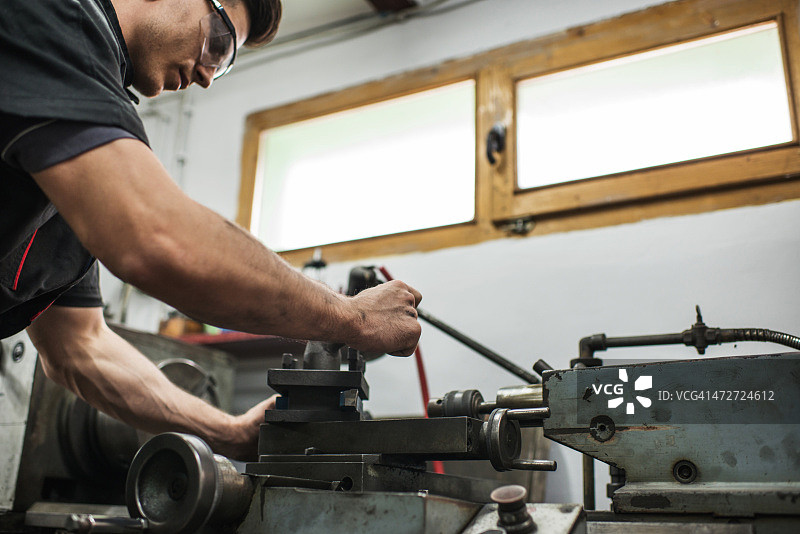 在车间使用钻头的年轻工人图片素材