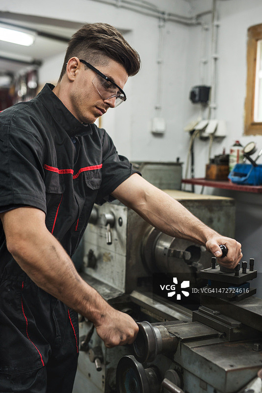 年轻修理工在车间使用车床图片素材