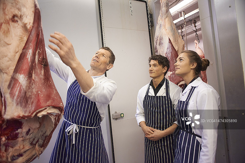 肉类批发店里的屠夫师傅教徒弟图片素材
