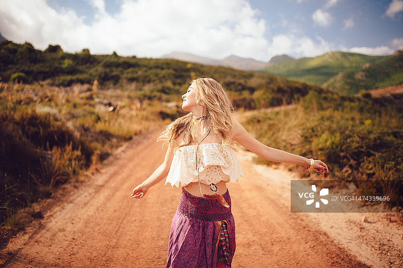 在乡村土路上快乐的波西米亚风女孩图片素材