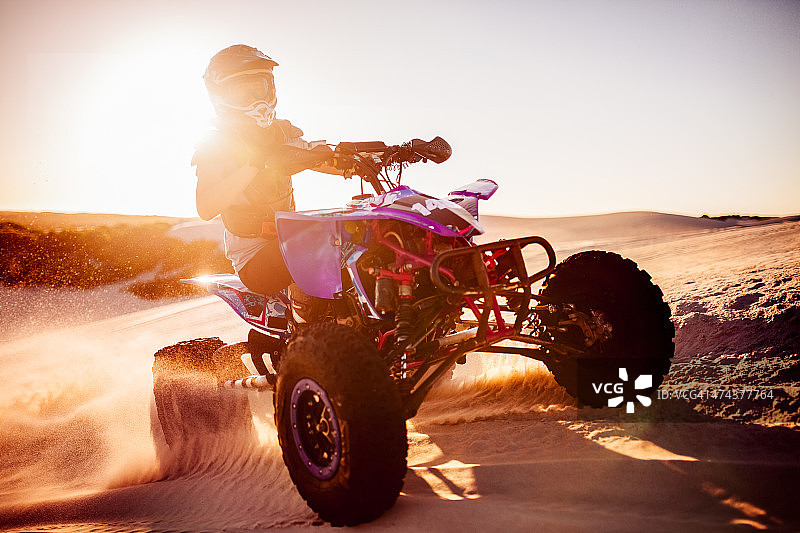 沙漠比赛中，阳光下的四轮摩托车手图片素材