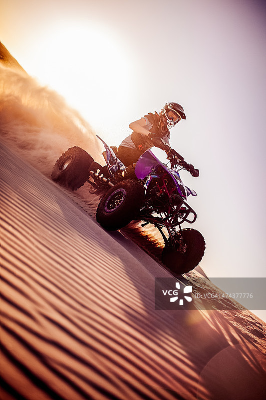 沙漠竞赛中沙丘上的四轮摩托车手图片素材