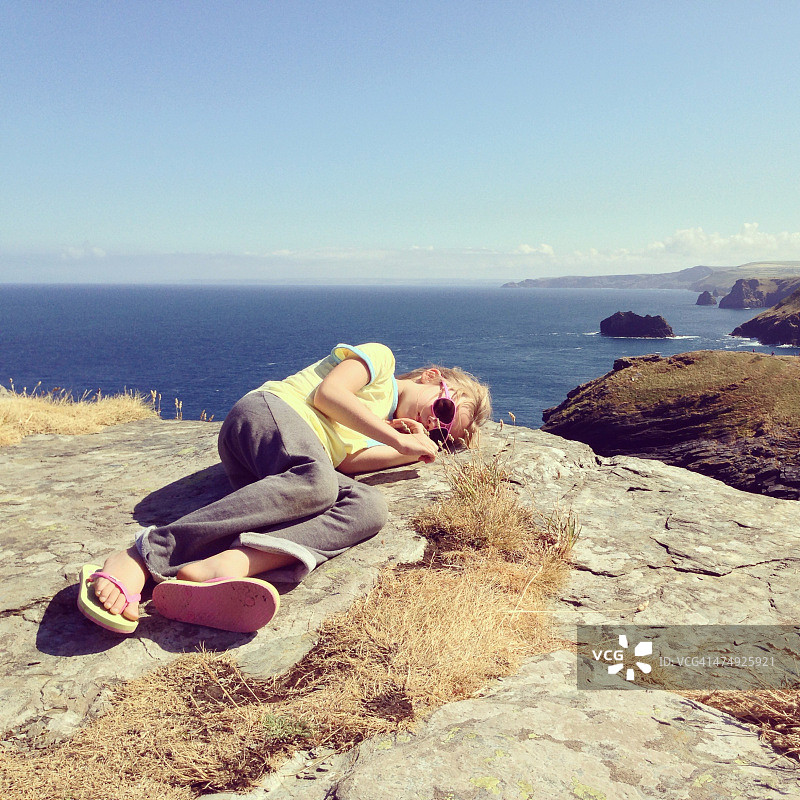 儿童躺在海岸悬崖边的岩石上图片素材