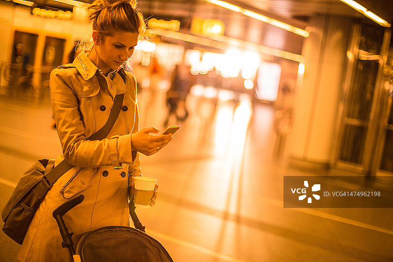 在户外使用智能手机的年轻妈妈图片素材