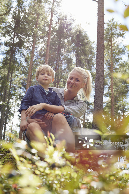 男孩坐在森林里母亲的腿上图片素材
