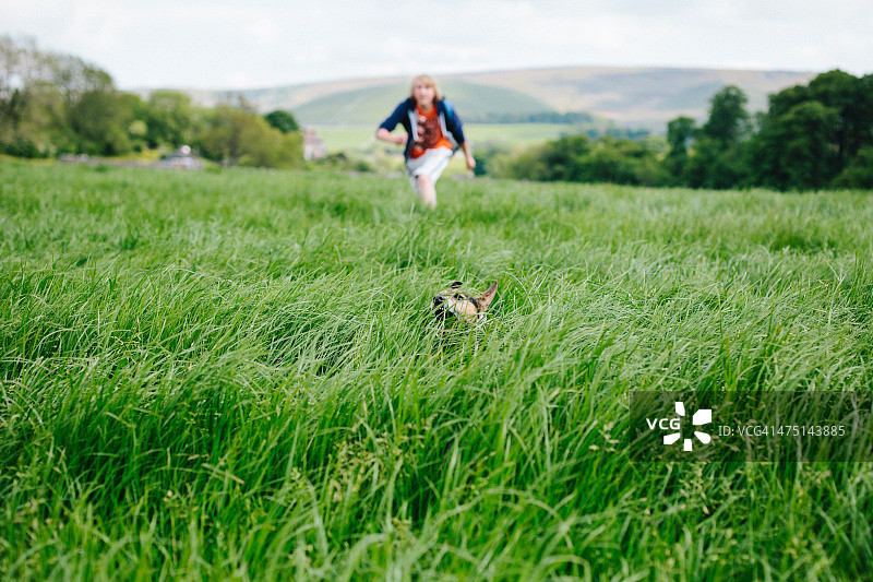 年轻男人和他的狗在草地上奔跑图片素材