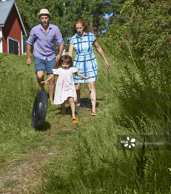 父母和女儿在瑞典耶夫勒Utvalnas的路上滚动轮胎图片素材