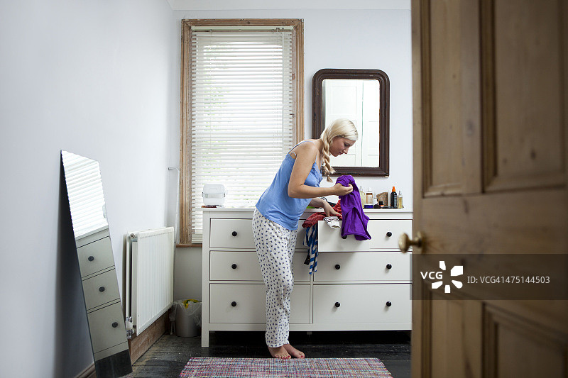 年轻女子在卧室里决定穿什么衣服图片素材