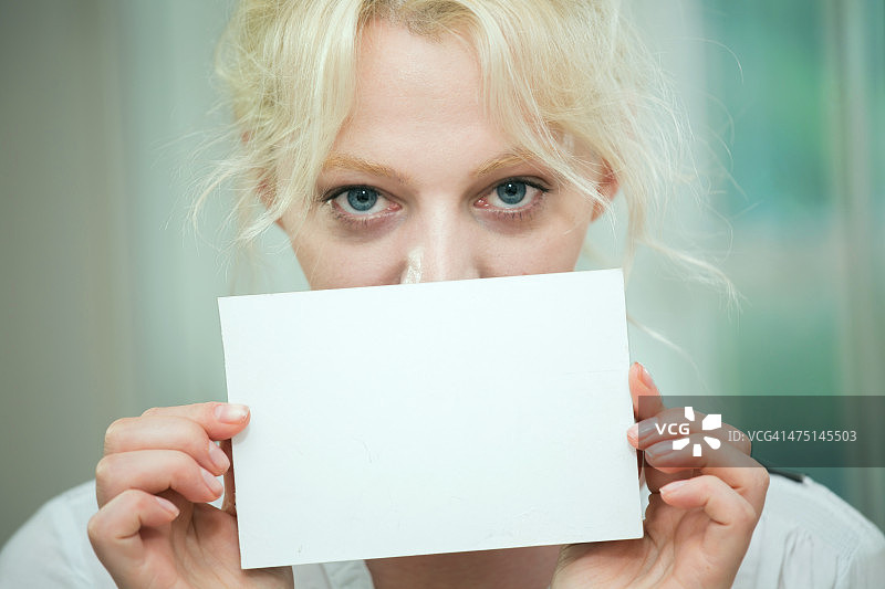 年轻女人手持空白卡片遮脸图片素材
