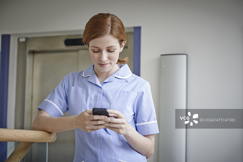 女护士在医院电梯外看手机图片素材