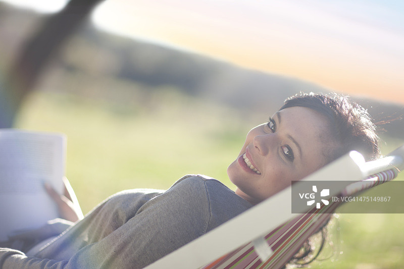 年轻女人斜倚在躺椅上看书图片素材