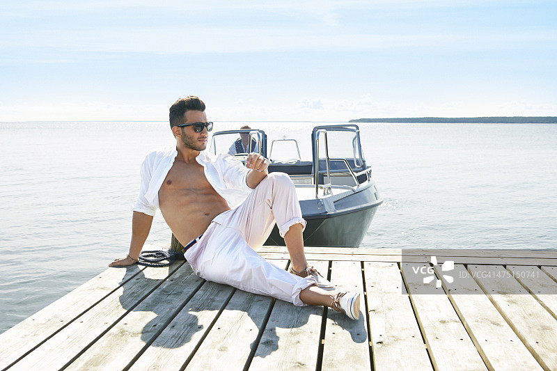 年轻男人坐在瑞典耶夫勒的码头上图片素材