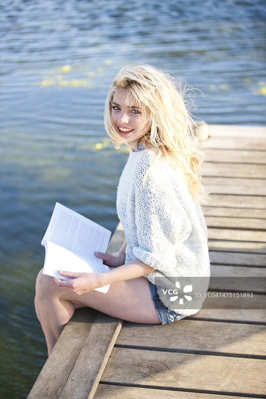 坐在码头上看书的年轻女人图片素材