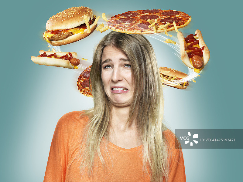 年轻女子厌恶地看着头上飞舞的快餐图片素材