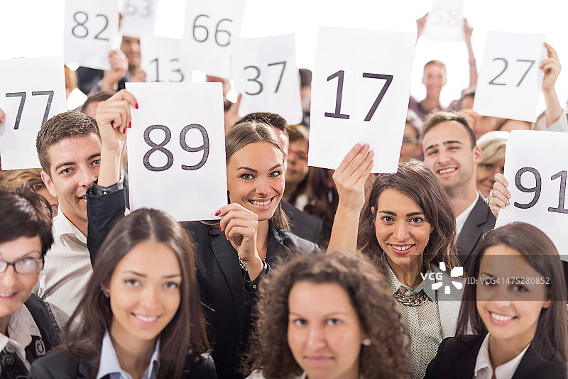 一群快乐的商人举着拍卖号码图片素材