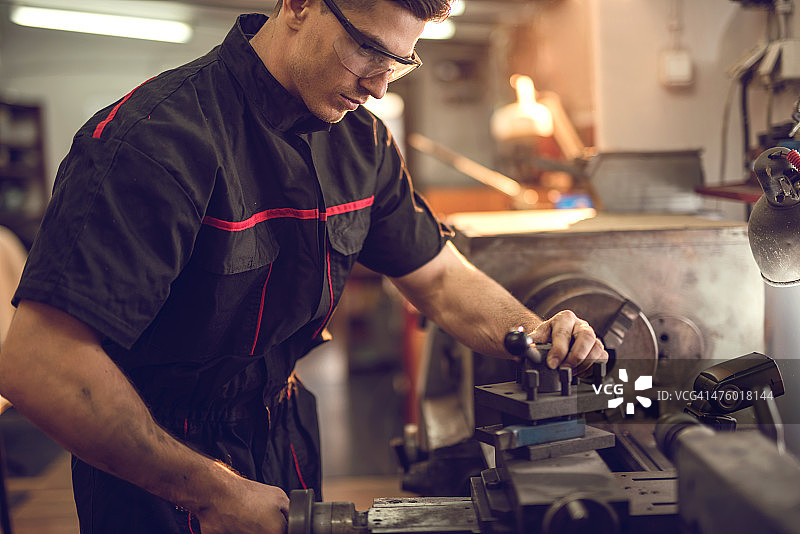 年轻修理工在车间使用车床图片素材