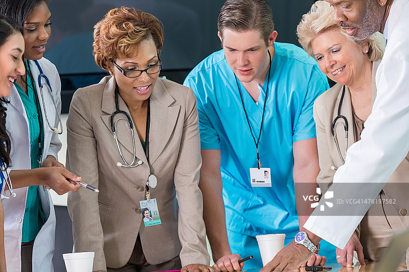 不同肤色的医疗团队在会议中查看病人图表图片素材
