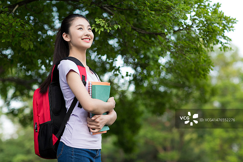 户外手持笔记本微笑的女学生图片素材